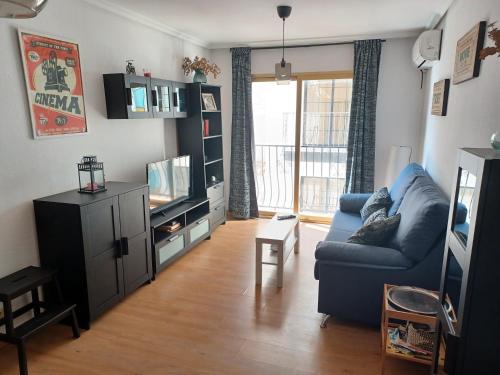 sala de estar con sofá azul y TV en Apartamento Welcome, en Benidorm