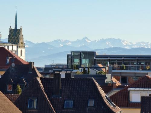 einen Blick auf die Dächer von Gebäuden mit Bergen im Hintergrund in der Unterkunft BodenSEE CITY APARTMENTS Friedrichshafen in Friedrichshafen