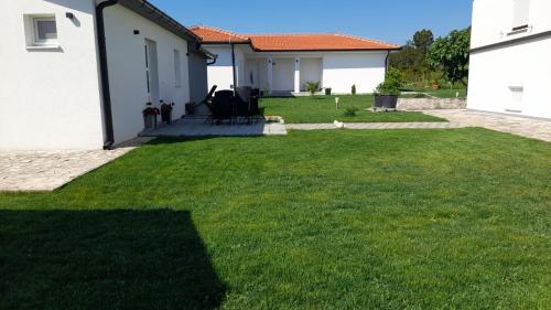 a yard with green grass and a house at Apartment Kravica in Ljubuški