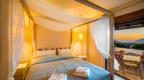 a bedroom with a canopy bed with a balcony at Gasparakis Villas in Plakias