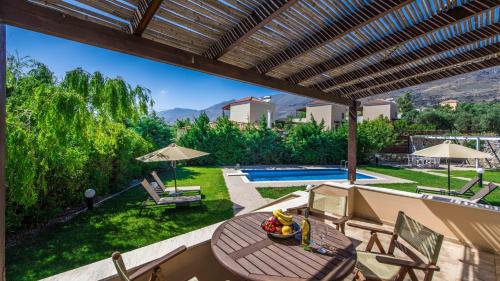 a patio with a table and chairs and a pool at Gasparakis Villas in Plakias