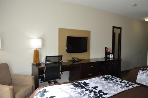 a hotel room with a bed and a desk with a television at Sleep Inn & Suites Elk City in Elk City