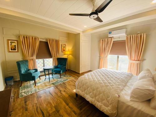 a bedroom with a bed and two chairs and a table at Holidazzle Serviced Apartments Bahria Town in Rawalpindi