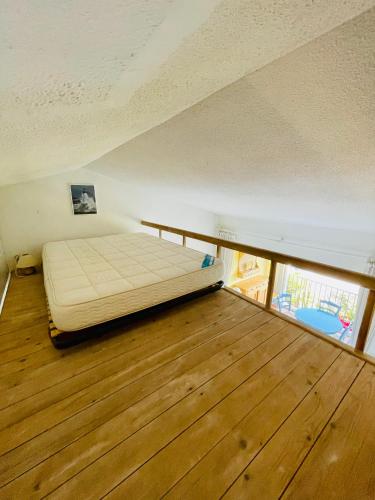 a bed in a room with a wooden floor at Bel appartement avec mezzanine, vue mer et piscine in Cogolin