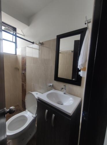 a bathroom with a toilet and a sink and a mirror at El buen descanso in Fusagasuga