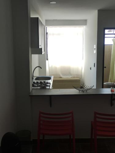 a kitchen with two red chairs and a window at El buen descanso in Fusagasuga