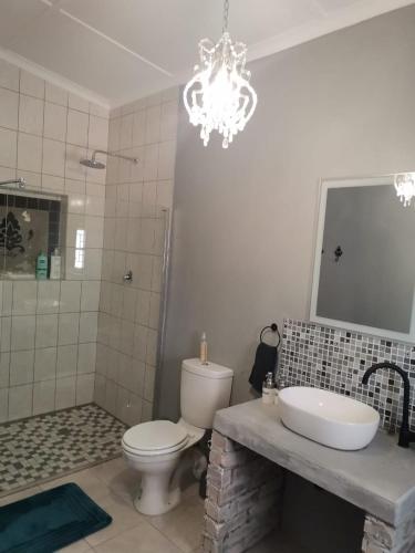 a bathroom with a toilet and a sink and a chandelier at Hartland Gastehuis/Guesthouse in Vredendal