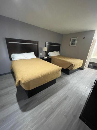 two beds in a hotel room with wood floors at The Kinder Inn in Kinder