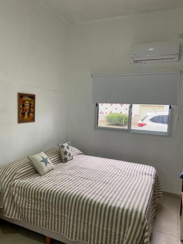 a bedroom with a bed with a striped sheets and a window at Soya Departamentos PB B in Junín