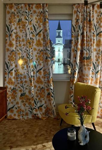 a room with a window with a yellow chair and a table at Apartament Antresola Stary Rynek in Zielona Góra