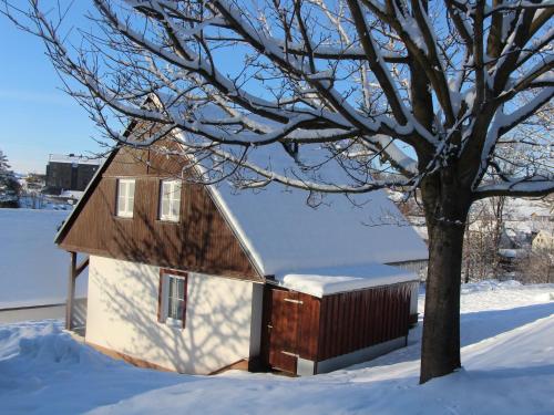 a small house in the snow next to a tree at Chata Větrník u Černého dolu v Krkonoších in Lauterwasser