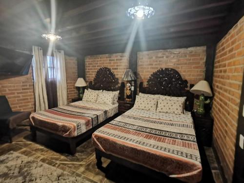a bedroom with two beds and a brick wall at Hotel Meson del Refugio in Guanajuato