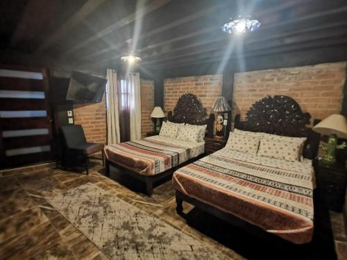 a bedroom with two beds and a chair at Hotel Meson del Refugio in Guanajuato