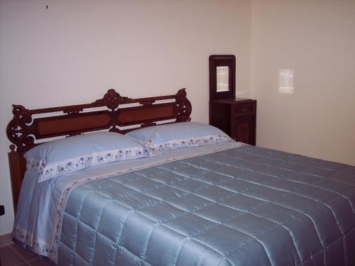 a bedroom with a blue bed with a wooden headboard at B&B Tramonto d'Oro in Castel del Monte