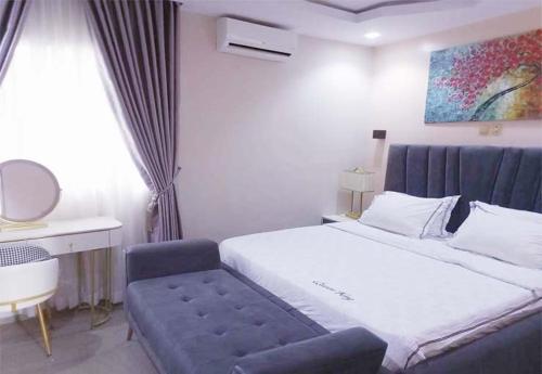 Schlafzimmer mit einem großen Bett und einer blauen Bank in der Unterkunft Westpark Luxury Apartments in Ikeja