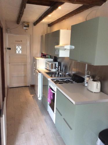 a kitchen with green cabinets and a stove top oven at Cwmbach Guest House in Neath