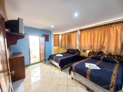 a hotel room with two beds and a television at Hotel Nakbé Atitlán in Panajachel
