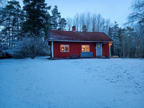 a red cabin in the snow with a snow covered yard at Lidsbergs torp i Ölme från år 1910 Ett eget mysigt torp med kakelugn, lågt i tak, sovrum med dubbelsäng och 2 enkelsängar på loft med snedtak bäddsoffa i v-rum trädgård med gasgrill in Kristinehamn