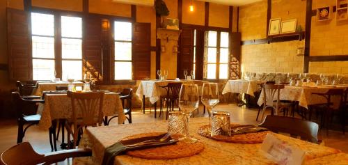 un comedor con mesas, sillas y ventanas en Hotel Judería Valle del Jerte en Cabezuela del Valle