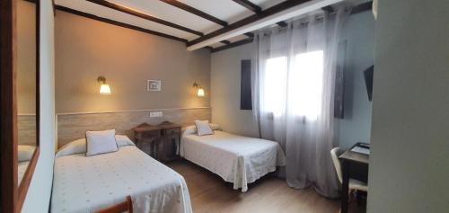 a small room with two beds and a window at Hotel Judería Valle del Jerte in Cabezuela del Valle