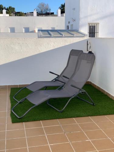 a chair sitting on the side of a building at ATICO LA ILUSION CON PARkING in Sanlúcar de Barrameda