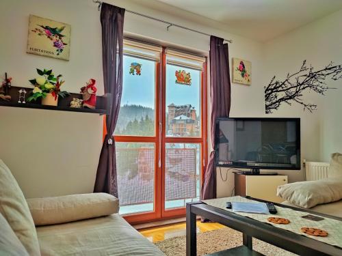 a living room with a couch and a large window at APARTMAN SNOW Vlašić in Vlasic