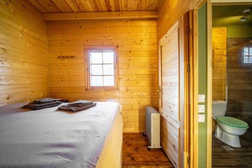 a room with a bed and a bathroom with a toilet at Wood Cabin by the River - for Nature Lovers in Vytina