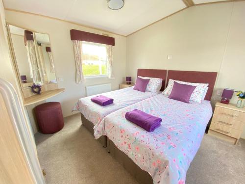 a bedroom with a large bed with purple pillows at Lavender Lodge, Accessible in South Cerney