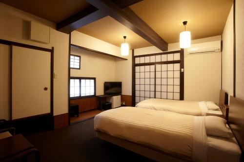 a hotel room with two beds and a tv at Koyado Enn in Toyooka