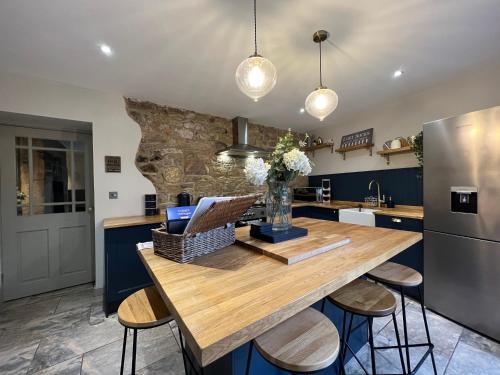 a kitchen with a wooden table and stools at Rose Cottage in Morpeth