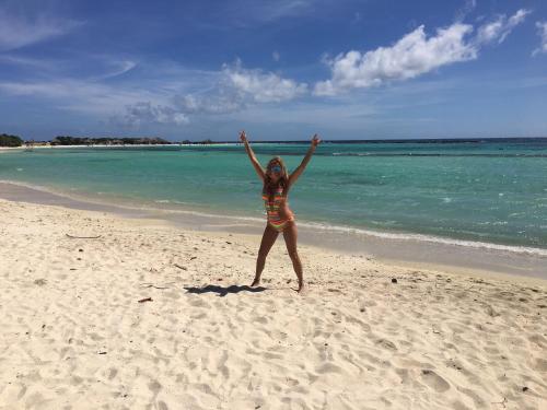 uma mulher parada numa praia com os braços no ar em Yoyita Suites Aruba Villa em Palm-Eagle Beach