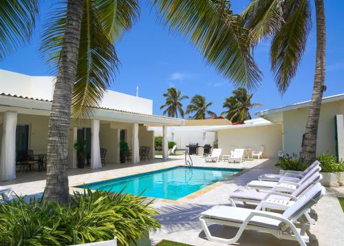 une villa avec une piscine et des palmiers dans l'établissement Yoyita Suites Aruba Villa, à Palm-Eagle Beach