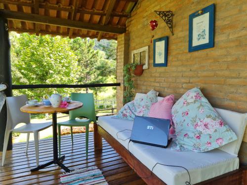 a couch sitting on a porch with a laptop on it at Pousada Vale Monte Azul in Santo Antônio do Pinhal