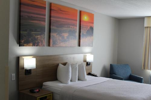 a hotel room with a bed and a blue chair at Days Inn by Wyndham Colby in Colby