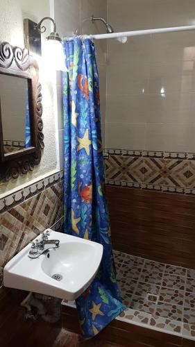 a bathroom with a sink and a shower curtain at Hotel Nakbé Atitlán in Panajachel