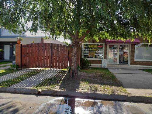 un árbol frente a una tienda con una valla en Casa Con Pileta En Roldan en Roldán