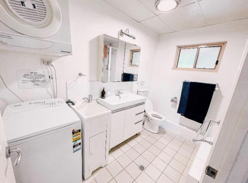 a white bathroom with a sink and a refrigerator at Oasis on the Hawkesbury - Water Views in Brooklyn