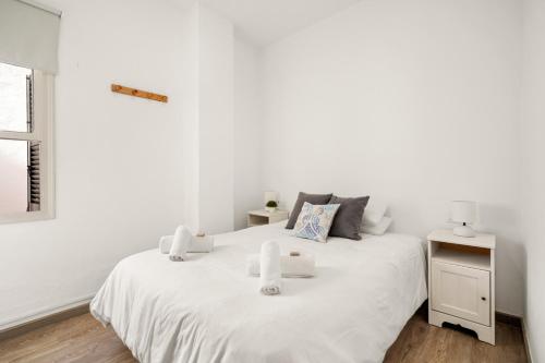 a white bedroom with a white bed and a window at Apartamento Sa Mesquida 9 in Cala Llonga
