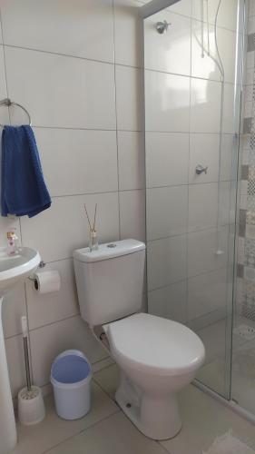 a white bathroom with a toilet and a glass shower at Quarto,em casa compartilhada in São José