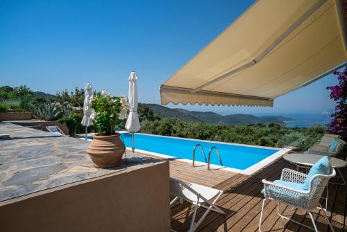 a villa with a swimming pool and a patio with an umbrella at Luxury villa + guest house couchers de soleil mer in Skiathos Town