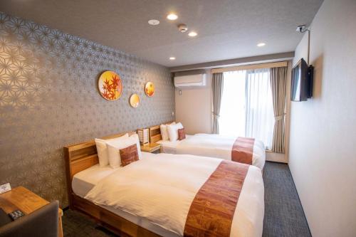 una camera d'albergo con due letti e una televisione di Stay SAKURA Kyoto Gion North a Kyoto