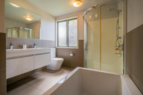 La salle de bains est pourvue d'une baignoire, d'un lavabo et d'une douche. dans l'établissement Matarangi Lakeside Gem - Golfers Dream!, à Matarangi