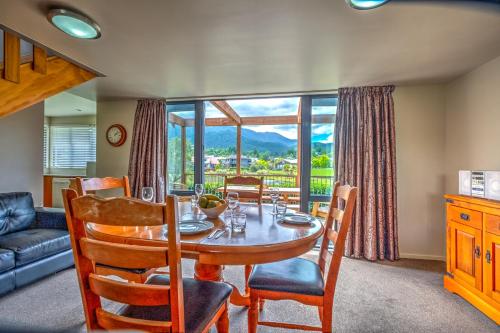a dining room with a table and chairs and a large window at *** LAKE VILLA 459 *** in Hanmer Springs