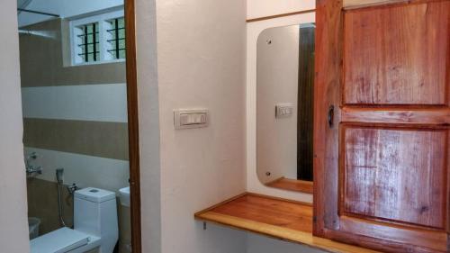 a bathroom with a wooden door and a mirror at Birds Murmur Camp, Thattekkad in Cochin