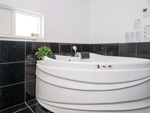 uma banheira branca numa casa de banho com azulejos pretos em Holiday home Sydals LXI em Neder Lysabild