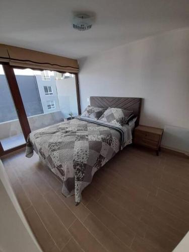 um quarto com uma cama e uma grande janela em Edifico claro solar piso 16 em Temuco