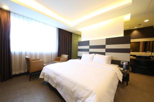 a hotel room with a large white bed and chairs at Moonbay Hotel in Busan