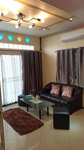a living room with a black couch and a table at Touch the Wind in Chaiyaphum