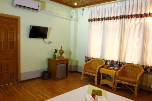 Habitación con TV, mesa y sillas. en Sandalwood Hotel, en Nyaung Shwe