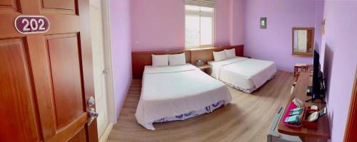 a bedroom with two beds in a room with pink walls at Coast Shan Shui B&B in Magong